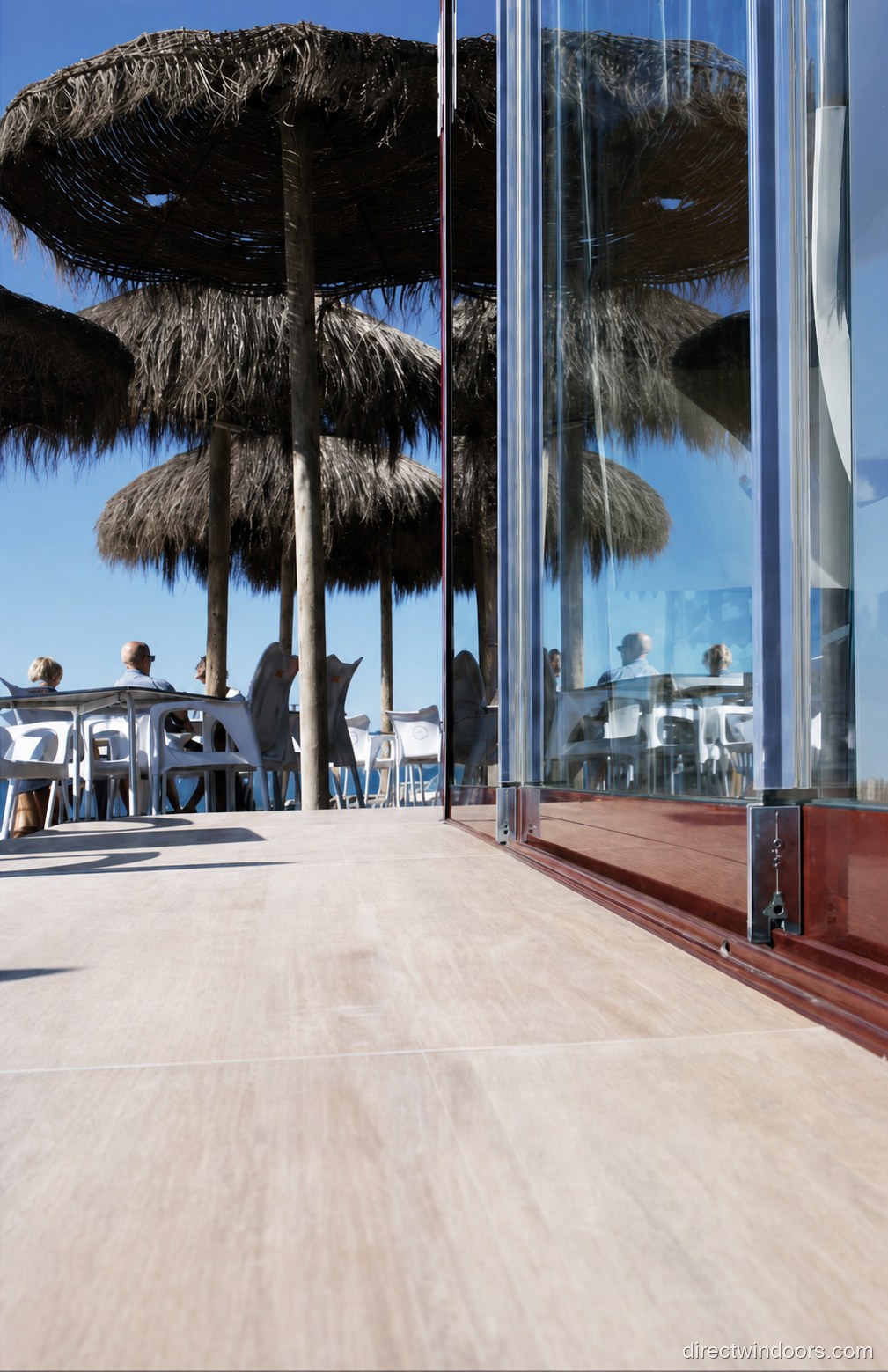 Frameless glass walls at an open-air beach bar with palm trees