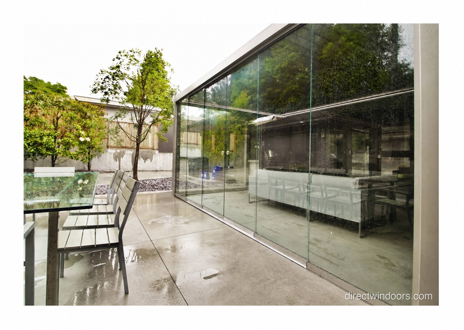 Frameless glass walls protecting an outdoor patio during rain