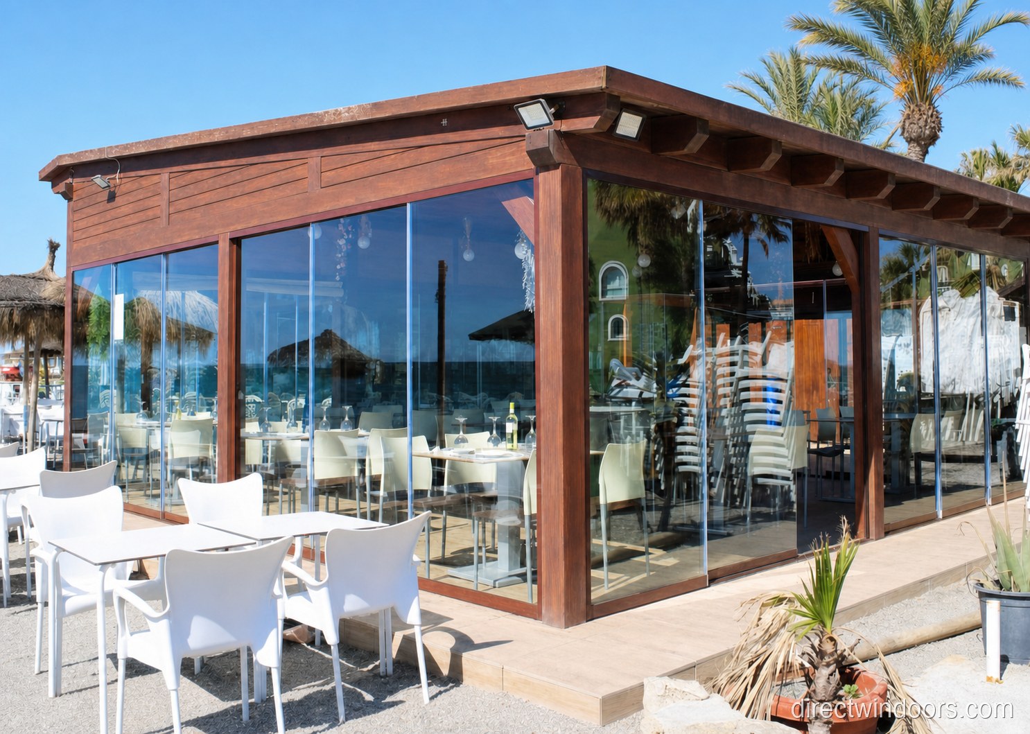 Frameless glass walls at a rustic palm-shaded restaurant patio