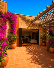 108 inch by 80 inch black aluminum bifold door shown open in a courtyard. Room setting shown is illustrative.
